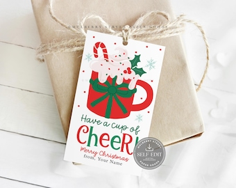 May include: A Christmas gift tag with a red mug design, topped with whipped cream and a candy cane. The tag reads "Have a cup of Cheer! Merry Christmas from, Your Name." The tag is tied to a wrapped gift with twine.