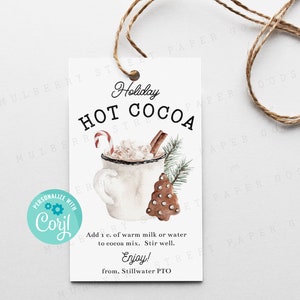 Puede incluir: Una etiqueta de regalo blanca con una ilustración de acuarela de una taza de chocolate caliente con un bastón de caramelo, una rama de canela y una galleta de jengibre. El texto en la etiqueta dice "Holiday Hot Cocoa" e incluye instrucciones para hacer el chocolate caliente. La etiqueta está atada con un cordel.