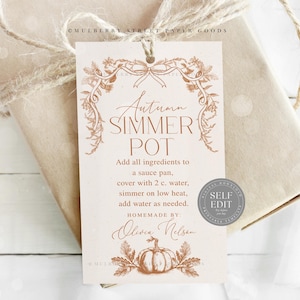 以下が含まれることがあります： 「Autumn Simmer Pot」の文字が装飾的なフォントで書かれたギフトタグ。説明とカボチャのイラストが描かれています。タグは、ひもで包まれたギフトに結び付けられています。
