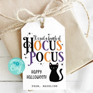 May include: A white gift tag with the text "It's just a bunch of Hocus Pocus" in black, orange, and purple. A black cat silhouette and the words "Happy Halloween!" are also featured. The tag is tied to a wrapped gift.