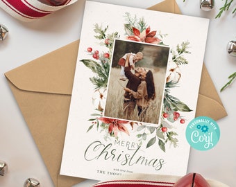 May include: A Christmas card with a watercolor floral border in shades of green, red, and white. The card features a photo of a family with a child being held up in the air. The text "Merry Christmas" is written in cursive with the words "with love from" and "THE THOM" below. The card is personalized with "Cori" in a teal circle.