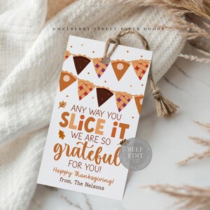 May include: A white Thanksgiving gift tag with a pie slice banner and the text "Any way you slice it, we are so grateful for you!" The tag is tied with twine and includes the text "Happy Thanksgiving!" and "from, The Nelsons."