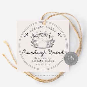 Puede incluir: Una etiqueta cuadrada de color blanquecino con un dise&ntilde;o circular que presenta un pan de masa madre. El texto dice "FRESHLY BAKED Sourdough Bread" y "Handmade by: BETHANY NELSON 651.555.1212". La etiqueta est&aacute; atada con hilo natural.