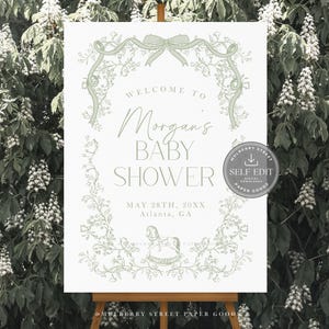 Pu&ograve; includere: Un cartello per baby shower su un cavalletto, con la scritta "Welcome to Morgan's Baby Shower" in un elegante carattere. Il design include elementi floreali e un'illustrazione di un cavallo a dondolo, con la data e il luogo sottostanti.