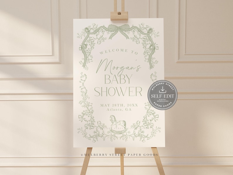 Pu&ograve; includere: Un cartello per baby shower su un cavalletto. Il cartello presenta un design floreale verde attorno al testo "Welcome to Morgan's Baby Shower". Vengono visualizzati anche la data e il luogo. Un adesivo di auto-modifica &egrave; nell'angolo.