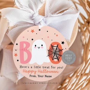 May include: A round Halloween gift tag with a light pink background. The tag features a ghost, spiderweb, and the word "BOO" in pink. Text reads "Here's a little treat for you! Happy Halloween From, Your Name."