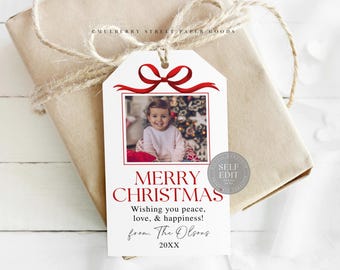 Peut inclure: Une étiquette cadeau blanche avec un nœud et un cadre rouges, avec une photo d'un enfant et les mots "JOYEUX NOËL". L'étiquette est attachée à un cadeau emballé avec de la ficelle.