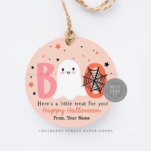 May include: A round, peach-colored Halloween gift tag with the word "BOO" in pink and orange, a white ghost, and a black spiderweb. The tag includes the text "Here's a little treat for you! Happy Halloween".