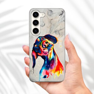 May include: A phone case with a watercolor painting of a dog on a marble background. The dog is painted in vibrant colors, including blue, green, yellow, orange, and red.