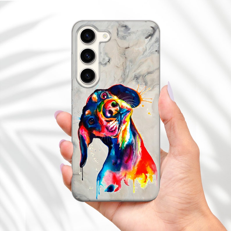 May include: A phone case with a watercolor painting of a dog on a marble background. The dog is painted in vibrant colors, including blue, green, yellow, orange, and red.