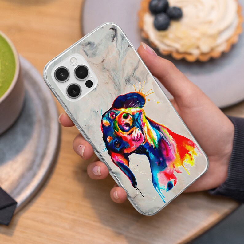 May include: A clear phone case with a marble design and a colorful abstract painting of a dog's head. The dog is painted in shades of blue, green, yellow, orange, and red.