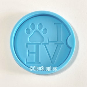 May include: Light blue silicone coaster mold with the word "LOVE" and a paw print in the center. The mold is for making resin coasters. The text "@ClanSupplies" is at the bottom of the mold.