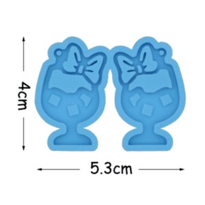 May include: A blue silicone mold for making resin earrings. The mold is shaped like two glasses with bows on top. The mold measures 5.3 cm wide and 4 cm tall.