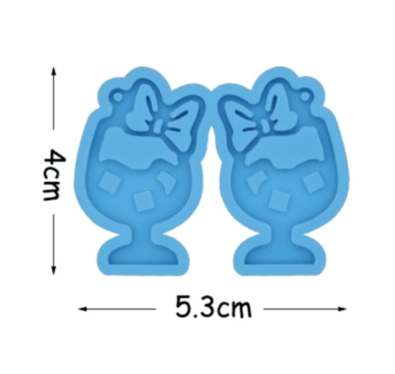 May include: A blue silicone mold for making resin earrings. The mold is shaped like two glasses with bows on top. The mold measures 5.3 cm wide and 4 cm tall.