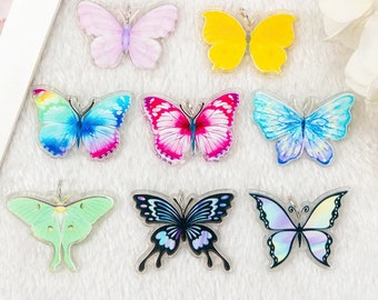May include: Assortment of eight colorful butterfly charms with clear acrylic backgrounds. The butterflies are in various colors, including pink, blue, green, yellow, and purple.
