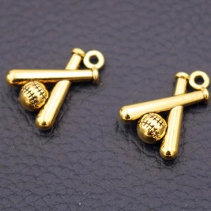 May include: Two gold-colored baseball charms. Each charm features a baseball and two crossed bats. The baseballs have stitched detailing. The charms have a loop at the top for attaching to jewelry or other crafts.
