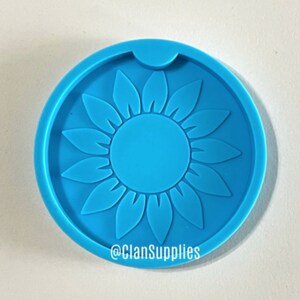May include: Blue silicone coaster mold with a sunflower design. The mold has a cutout for a cup or glass. The mold is made by @ClanSupplies.
