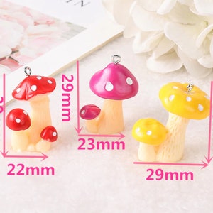 May include: Three mushroom charms with metal loops. The red mushroom set measures 30mm by 22mm. The pink mushroom set measures 29mm by 23mm. The yellow mushroom set measures 29mm by 29mm. Each mushroom features a light-colored stem and a spotted cap.