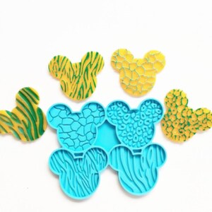 May include: A set of six silicone molds shaped like Mickey Mouse ears. The molds are blue and feature different animal print designs, including zebra, leopard, and giraffe.