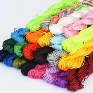 May include: A collection of colorful waxed cotton cords, perfect for crafting bracelets, necklaces, and other jewelry. The cords are arranged in a fan shape, showcasing a variety of vibrant hues.