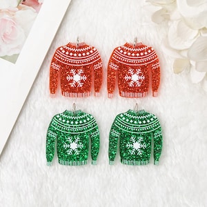 May include: Four Christmas sweater ornaments, two red and two green, with white snowflake designs. The ornaments are made of glitter and have a shiny finish.
