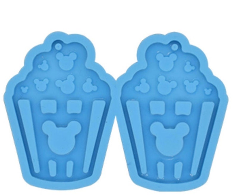 May include: Two blue silicone molds for making resin earrings. Each mold features a popcorn bucket with Mickey Mouse ears and popcorn pieces.
