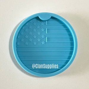 May include: A light blue silicone coaster mold with a raised design of the American flag. The mold has a cut-out for a cup or glass. The text "@ClanSupplies" is printed on the mold.
