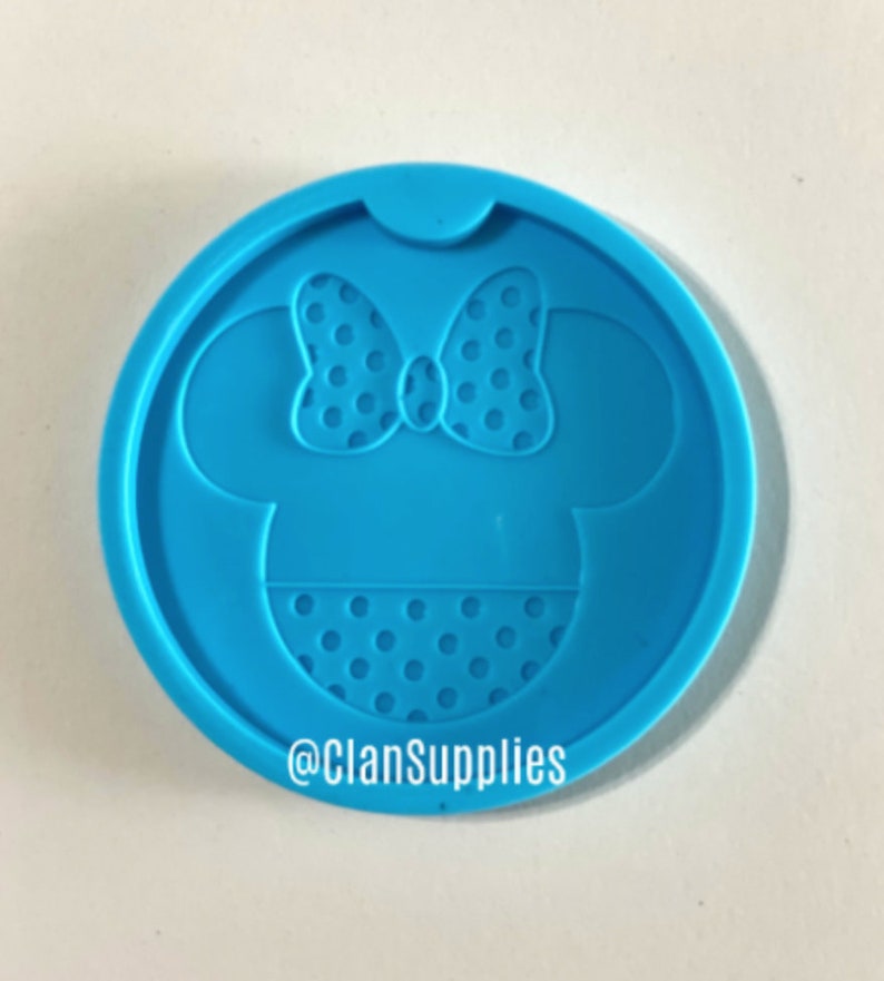 May include: Blue silicone mold with a Minnie Mouse design. The mold features a polka dot bow and dress.