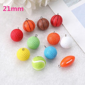May include: Assortment of 12 colorful 21mm sports ball charms, including basketball, golf ball, tennis ball, football, and baseball. Each charm has a silver loop for attaching to jewelry or crafts.