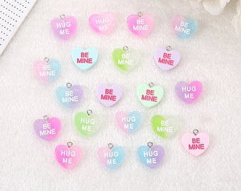 May include: Assortment of 17 heart-shaped charms with glitter and various pastel colors. The charms have the words "Hug Me" and "Be Mine" written on them.