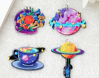 May include: Four colorful charm pendants with different designs. One features a mushroom and flower design, another a galaxy planet, a third a cup of coffee with a galaxy design, and the last a planet with an astronaut.