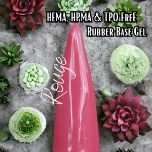 May include: A vibrant pink nail gel applicator with the word "Rouge" in cursive script. The text "HEMA, HPMA & TPO FREE Rubber Base Gel" is displayed above the applicator. The image is decorated with various succulent plants in shades of green and burgundy.