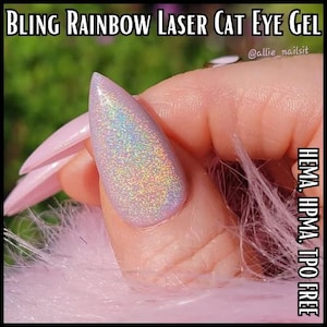 May include: A close-up of a fingernail with a light purple gel polish. The nail has a holographic, rainbow effect. The image also shows the text "BLING RAINBOW LASER CAT EYE GEL" and "HEMA, HPMA, TPO FREE".