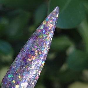 May include: A clear nail polish with iridescent glitter in shades of purple, blue, green, and gold.