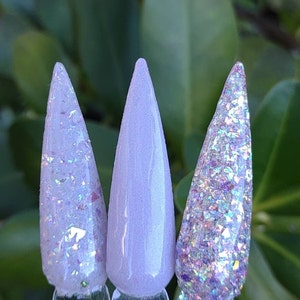 May include: Three nail polish colors in a light purple shade. The colors are a light purple with iridescent glitter, a solid light purple, and a light purple with iridescent glitter.