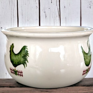 May include: White ceramic bowl with a green rooster design. The rooster is standing on a red fence. The bowl is perfect for serving snacks or holding small items.