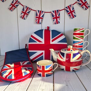 May include: A selection of kitchen items featuring the Union Jack flag. The set includes a teapot, mugs, an oven glove, and a tea cosy. A garland of Union Jack flags is strung above, creating a cohesive and patriotic display.