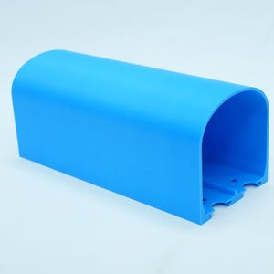 Pu&ograve; includere: Un oggetto di plastica blu brillante, arcuato, con una base rettangolare. L'oggetto ha una parte superiore liscia e curva e un interno aperto. La base presenta tre piccoli ritagli distanziati. L'oggetto &egrave; su sfondo bianco.