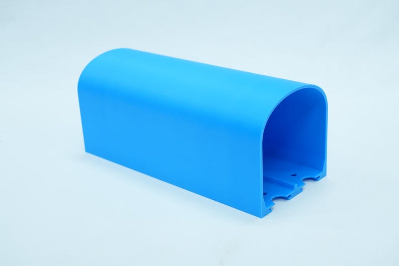 Pu&ograve; includere: Un oggetto di plastica blu brillante, arcuato, con una base rettangolare. L'oggetto ha una parte superiore liscia e curva e un interno aperto. La base presenta tre piccoli ritagli distanziati. L'oggetto &egrave; su sfondo bianco.