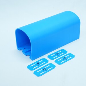 Pu&ograve; includere: Un componente in plastica blu brillante, arcuato, con quattro clip blu abbinate. Le clip presentano un logo "B" stilizzato. Il componente ha una parte superiore curva e un'estremit&agrave; aperta.