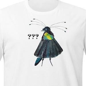 Könnte beinhalten: Weißes T-Shirt mit einer Aquarellillustration eines Paradiesvogels. Der Vogel hat einen schwarzen Körper, gelbe Akzente und lange Antennen. Der Text "???" steht über dem Vogel. Das T-Shirt ist aus weichem Material.