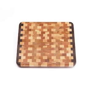 May include: A rectangular wooden cutting board with a checkered pattern of light and dark wood. The board has a dark wood border.