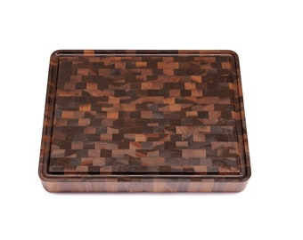 May include: A large, rectangular cutting board made of dark wood with a mosaic pattern. The board has a raised edge around the perimeter.