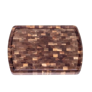 May include: A large, rectangular cutting board made of walnut wood. The board is made of many small pieces of wood that are arranged in a mosaic pattern. The board has a rounded edge.