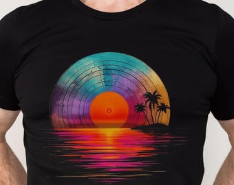 Op de afbeelding: Een zwart T-shirt met een kleurrijk vinylplaatontwerp. De plaat is geplaatst tegen een zonsondergang met palmbomen en een reflectie in het water.
