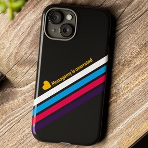 Op de afbeelding: Zwarte telefoonhoes met een diagonaal streepdessin in wit, blauw, roze en paars. De tekst "Monogamie is overrated" staat in geel met een geel hartje links van de tekst.