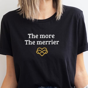May include: A black t-shirt with the text "The more The merrier" in white lettering and a gold infinity heart symbol.