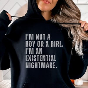 Op de afbeelding: Zwarte hoodie met de tekst "Ik ben geen jongen of meisje. Ik ben een existentiële nachtmerrie." in wit gedrukt.