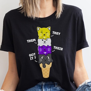 May include: Black t-shirt with a graphic of a stack of ice cream cones with cat faces. The ice cream cones are labeled "They", "Them", "Their", and "Got it?"