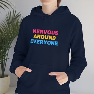 May include: A navy blue hoodie with the text "NERVOUS AROUND EVERYONE" in pink, yellow, and blue.